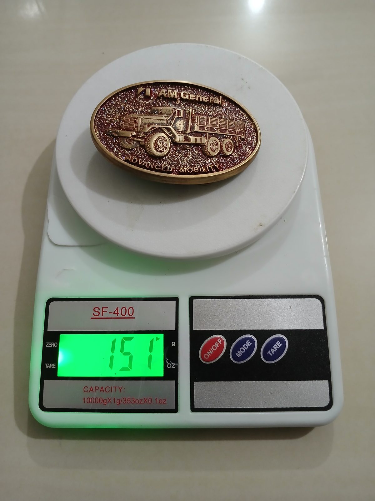 AM General Advanced Mobility Vintage Belt Buckle – On scale showing weight AM General Advanced Mobility vintage belt buckle – on scale showing weight