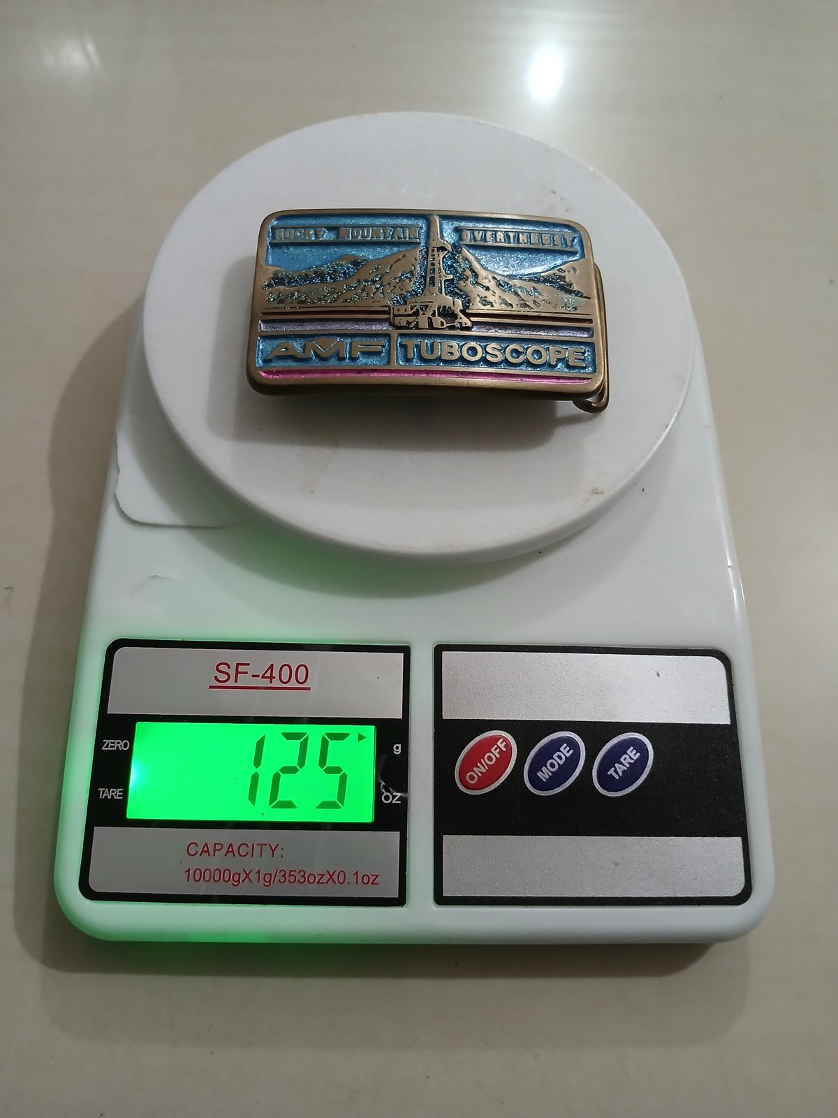 AMF Tuboscope Vintage Belt Buckle – On scale showing weight AMF Tuboscope vintage belt buckle – on scale showing weight