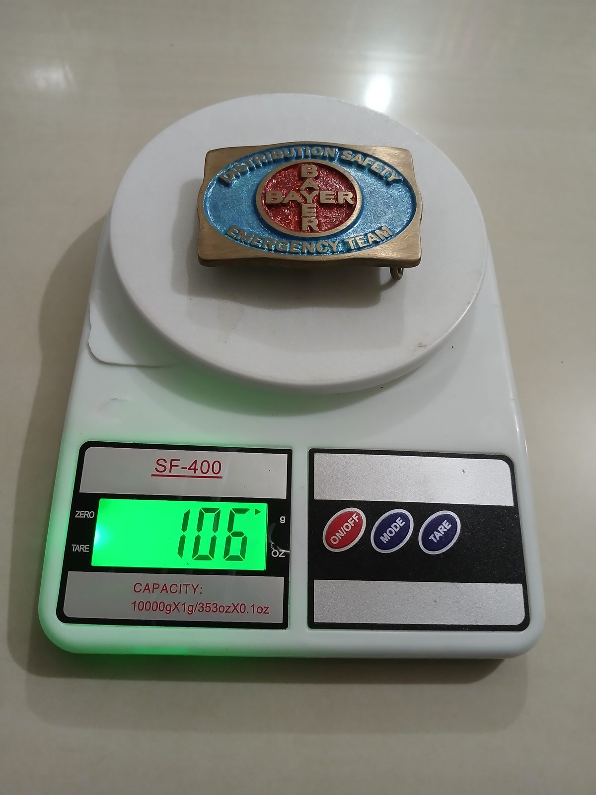 Bayer Emergency Team Vintage Belt Buckle – On scale showing weight Bayer Emergency Team vintage belt buckle – on scale showing weight