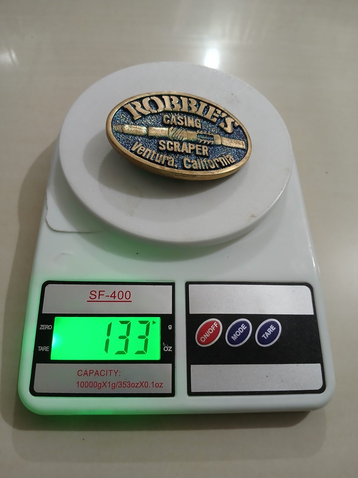 Casing Scraper Ventura California Vintage Belt Buckle – On scale showing weight Casing Scraper Ventura California vintage belt buckle – on scale showing weight