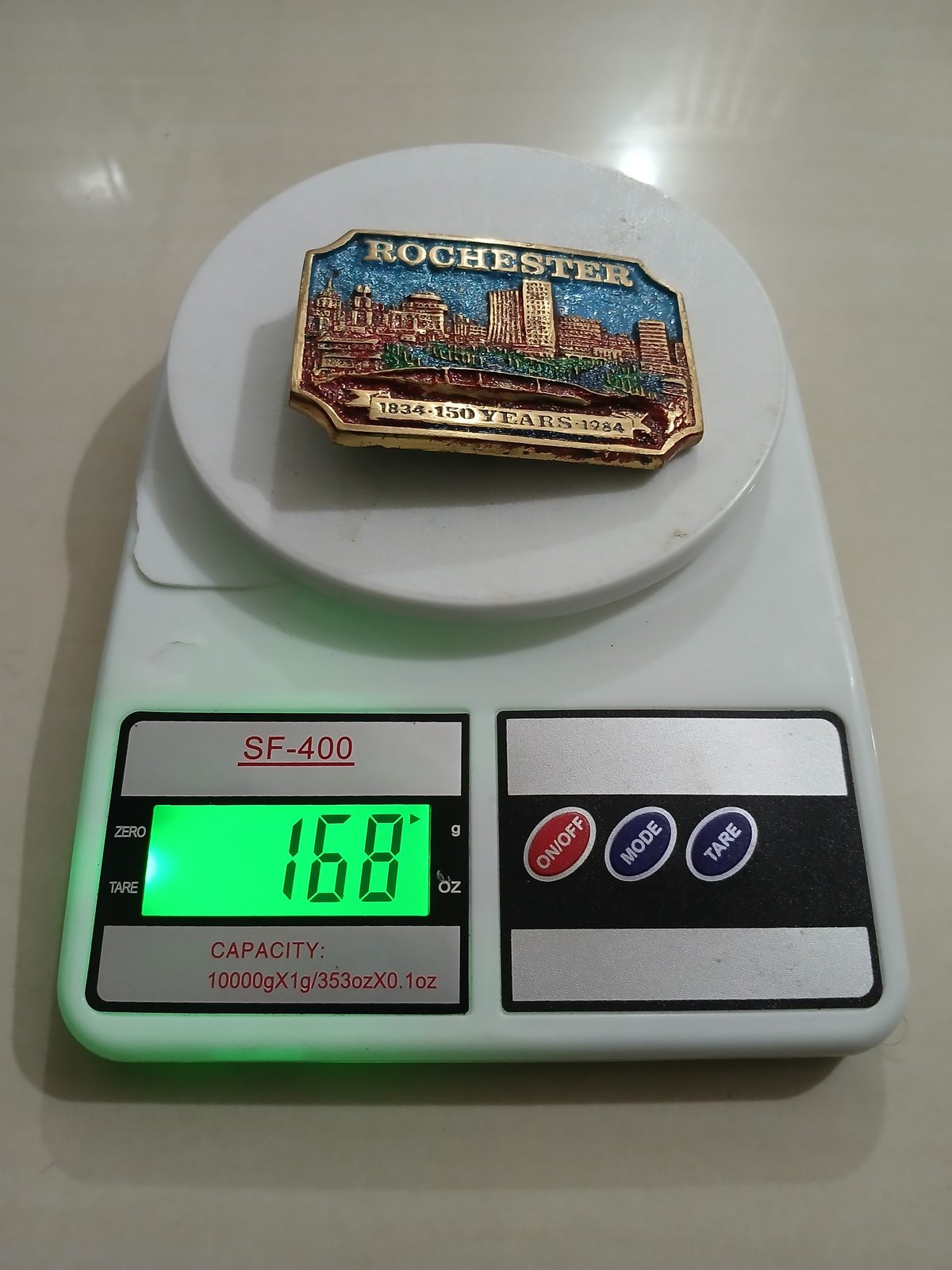 City Skyline 150 Years 1834-1984 Vintage Belt Buckle – On scale showing weight City Skyline 150 Years 1834-1984 vintage belt buckle – on scale showing weight