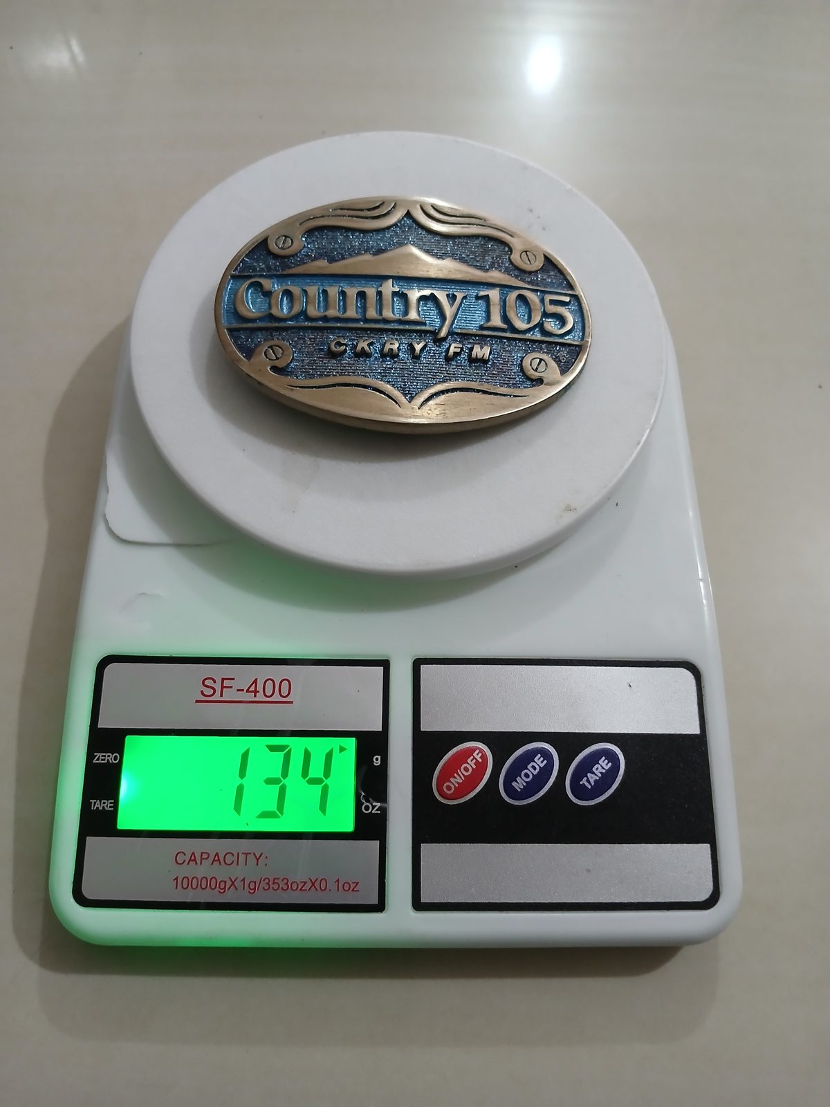 Country 105 CKRY FM Vintage Belt Buckle – On scale showing weight Country 105 CKRY FM vintage belt buckle – on scale showing weight