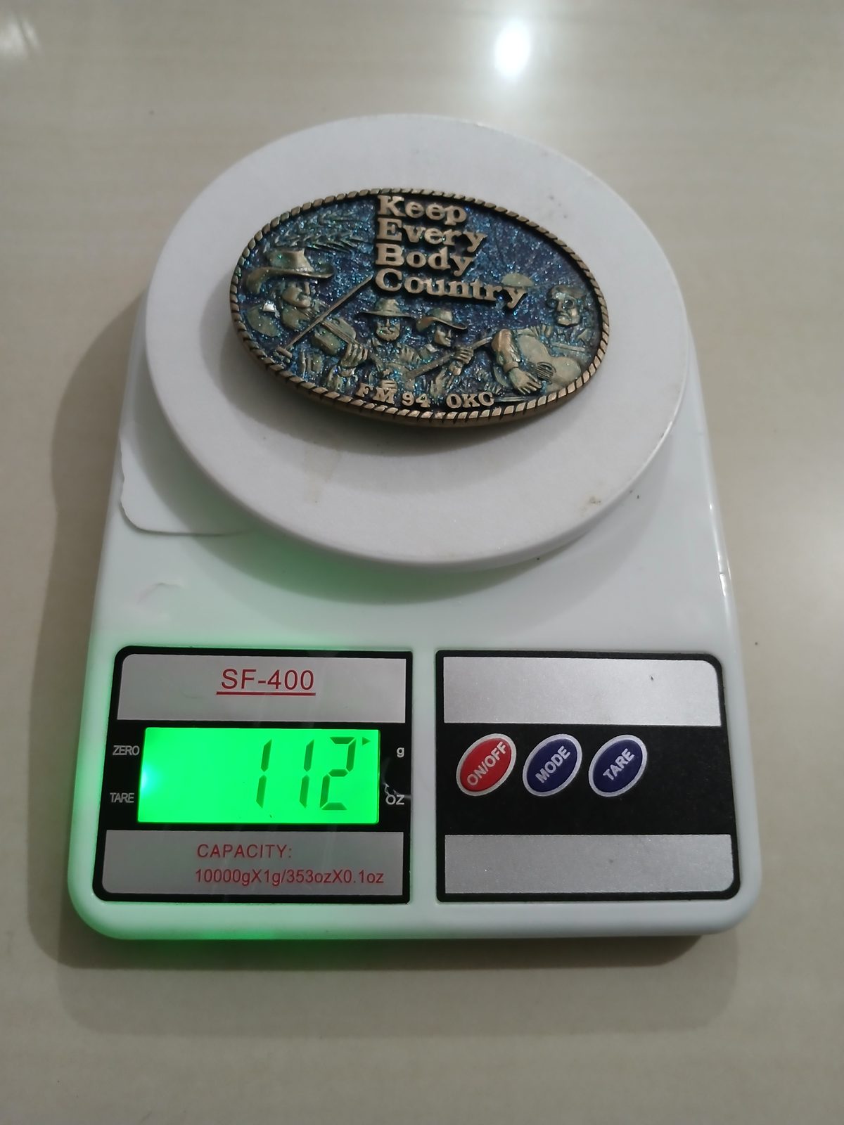 Keep Every Body Country FM94 OKC Vintage Belt Buckle – On scale showing weight Keep Every Body Country FM94 OKC vintage belt buckle – on scale showing weight