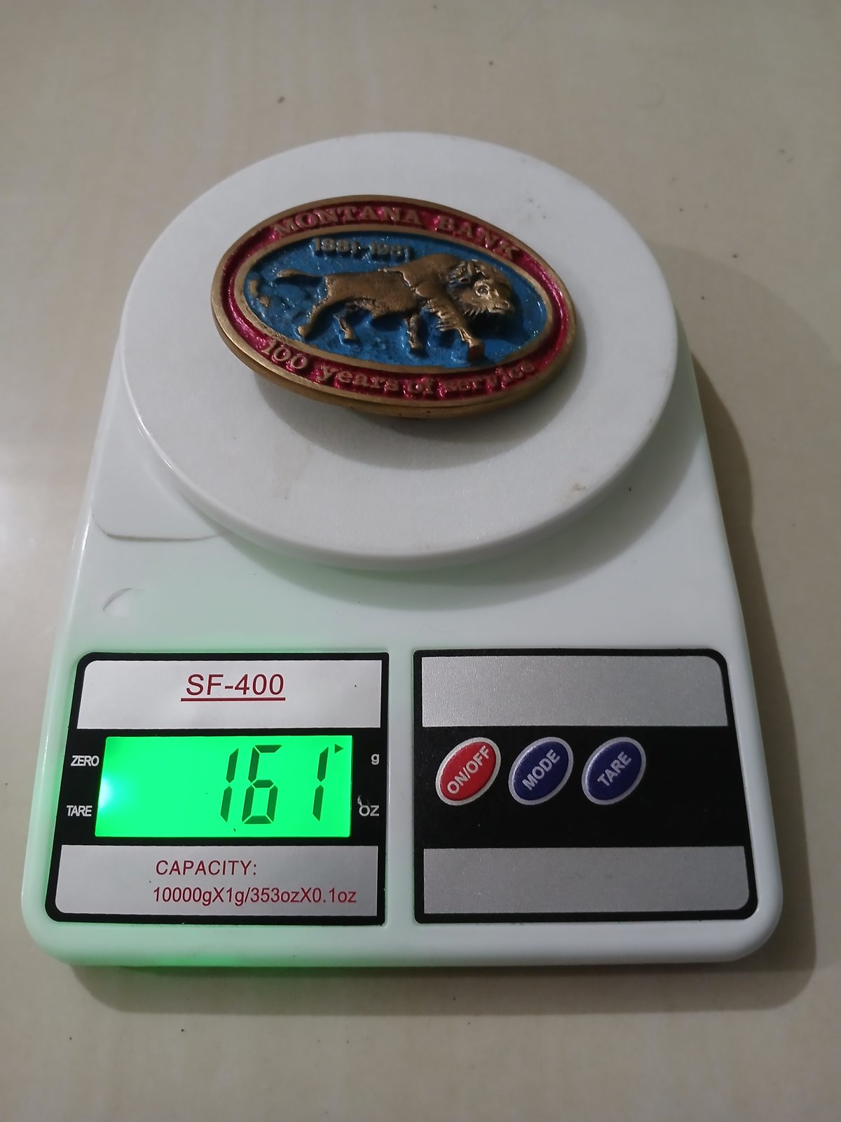Montana Bank 1881-1981 Vintage Belt Buckle – On scale showing weight Montana Bank 1881-1981 vintage belt buckle – on scale showing weight