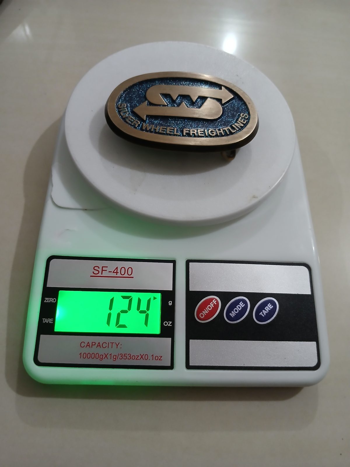 Silver Wheel Freightlines Vintage Belt Buckle – On scale showing weight Silver Wheel Freightlines vintage belt buckle – on scale showing weight