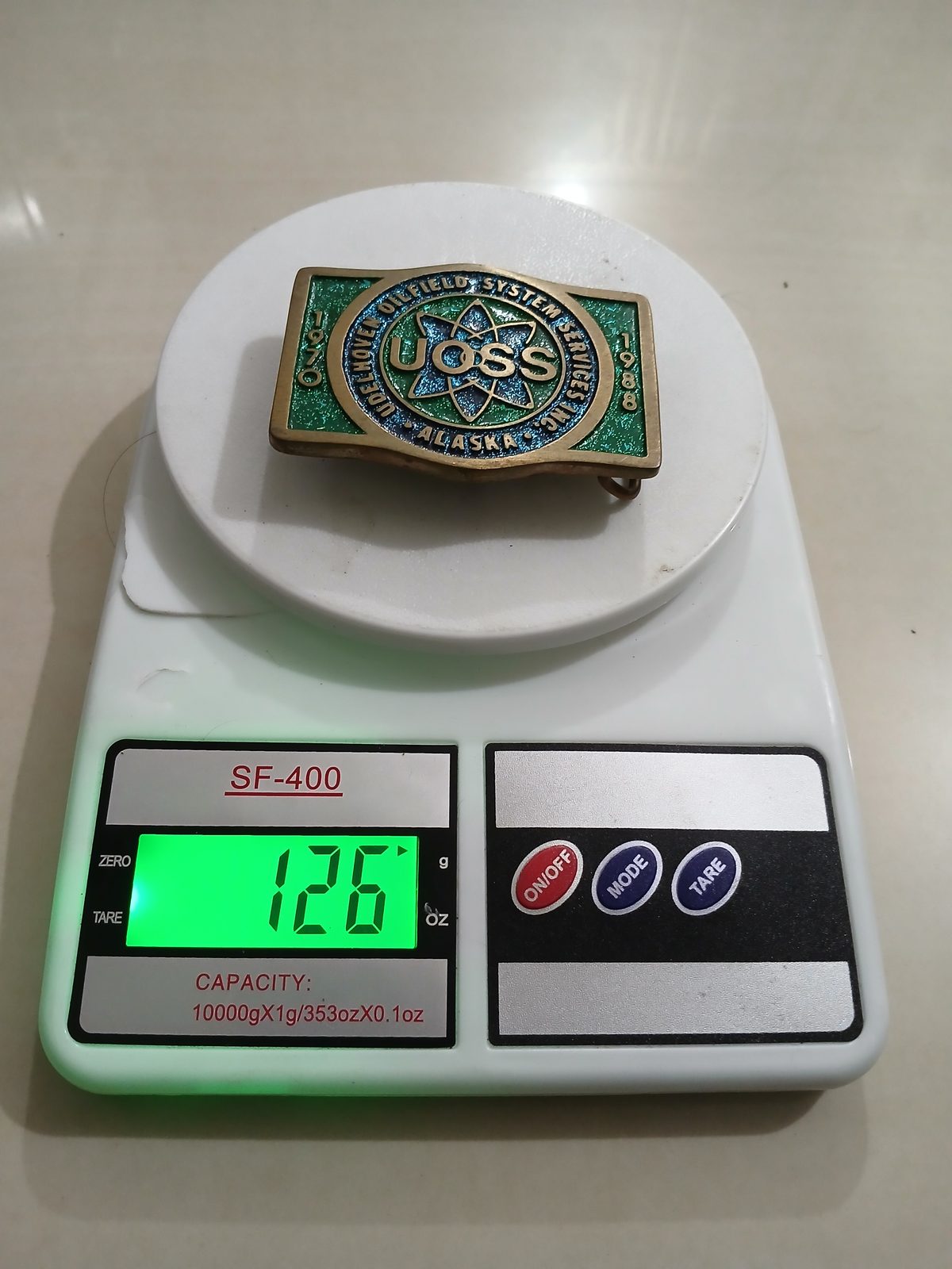 UOSS Udelhoven Oilfield Alaska Vintage Belt Buckle – On scale showing weight UOSS Udelhoven Oilfield Alaska vintage belt buckle – on scale showing weight